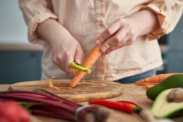 Close up of woman's hands peeling carrots