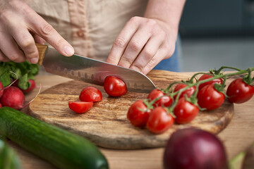 Woman cutting cherry tomatoes on wooden board