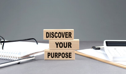 DISCOVER YOUR PURPOSE text on wooden block with notebook,chart and calculator, grey background