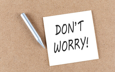 DON'T WORRY text on a sticky note on a cork board with pencil ,