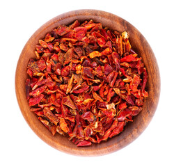 Dried red paprika flakes in wooden bowl, isolated on white background. Spices and herbs. Top view.