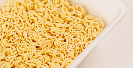 Dry instant noodles in styrofoam packaging. Dry pasta without spices and condiments. Macro.