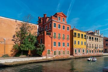 Fototapeta na wymiar Venetian street with bright houses and a sea channel. The residential area of Venice, Italy.