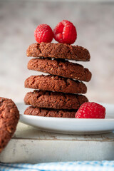 Oatmeal cookies with raspberries on bright background.