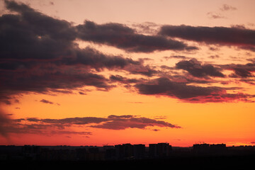 Dark clouds in the evening sunset sky with the setting sun. Dramatic sky during orange sunset