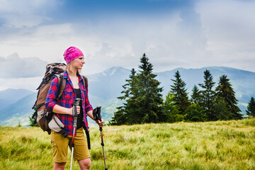 Fototapeta na wymiar Woman Traveler with Backpack hiking in the Mountains with beautiful summer landscape