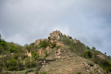 Naklejka premium the ruins of an ancient alpine settlement in the mountains of Dagestan against the backdrop of mountains and blue sky