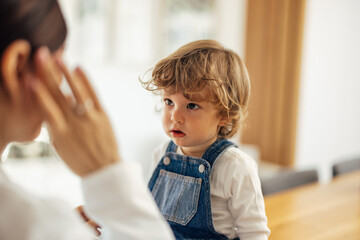 A female doctor at the home visit, a toddler being calm, looking