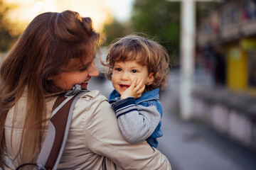 Portrait of a cute toddler, smiling at something, being carried in mom's hands.