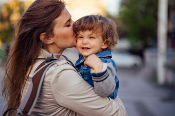 Young mother holding her son, giving him kisses on the head.