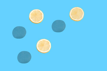 Minimal summer scene with three lemon slices and sharp shadows against sunny blue background. Creative copy space.