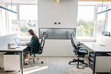 Young female programmer web developer working on computer software in modern office. Web Designer Woman working at her desk in open plan office