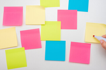 Blank Sticker notes on white background. hand with red marker ready to write. Mockup sticky Note Paper. empty sheets for notes on white bulletin board. Colored sticky notes