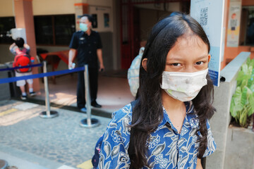 Asian elementary schoolgirl wearing face mask back to school again after covid pandemic