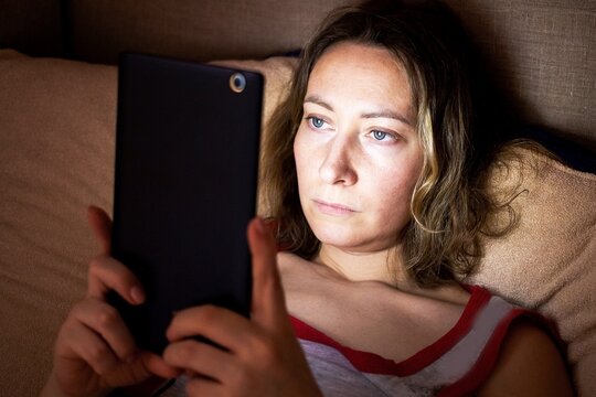 a young woman hides in bed at night and secretly spoils her eyesight watching movies on her phone