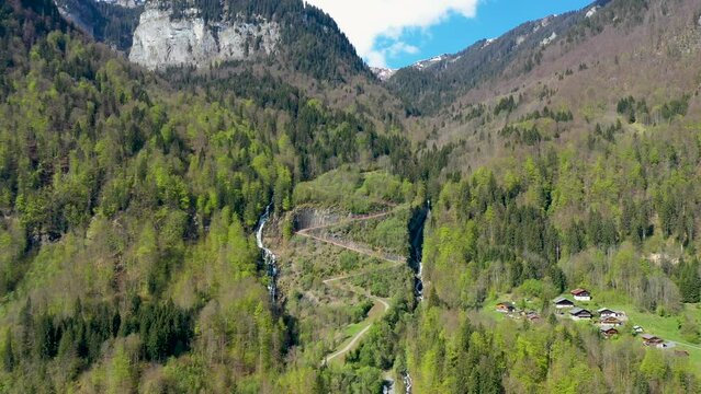 Stunning drone footage of Alpine Mountains, forests and waterfalls. Chalets nestle in the beautiful landscape near Sixt fer Cheval in the French alps.