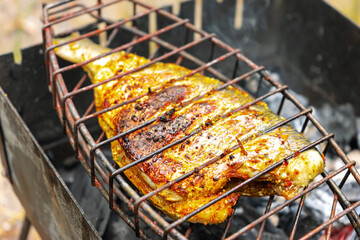 Grilled fish fried with lemon, citrus and spices, pepper. Exotic dietary marine fish. Dorado and perch in a restaurant recipe. Fish steak, barbecue, picnic. Fish cooked on fire coal on grill.