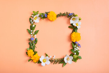 Summer or spring composition on a orangr background. Square frame from flowers and leaves with a copy space top view. Summer, spring floral concept