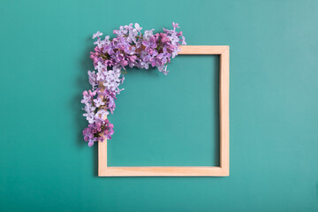 Summer or spring composition on a green background. Lilac flowers with wooden square with copy...