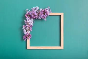 Gordijnen Summer or spring composition on a green background. Lilac flowers with wooden square with copy space top view. Summer, spring floral concept. © Alina