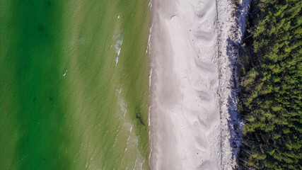 Top down view of the sandy beach, clear sea water and green forest in a sunny day.