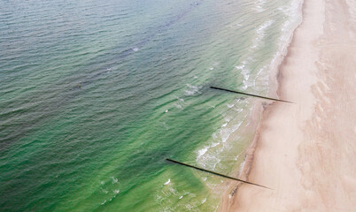 Top down view of the sea and sandy beach in a daylight. View of the breakwater. - obrazy, fototapety, plakaty