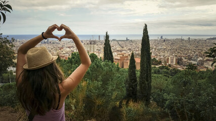 Female wearing a straw hat making a heart shape with her hands to Barcelona, Spain