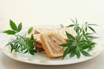 Sweet roll with marijuana oil on white plate. Cannabis kitchen. Layout of delicious dessert, top view close up.