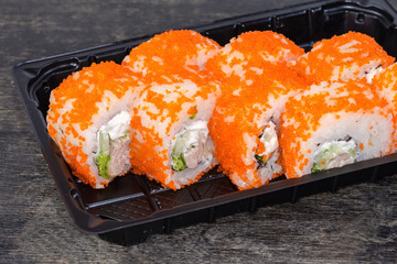 Sushi uramaki covered with flying fish roe in plastic container