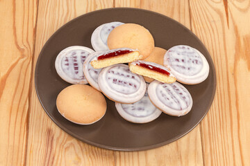 Cookies with white chocolate coating and jam filling on dish