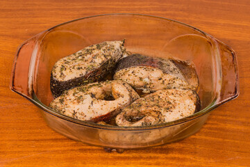 Baked trout pieces in glass baking dish on wooden table