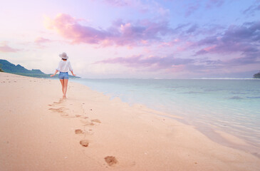 Vacation on the seashore. Back view of young woman walking away on the beautiful tropical white sand beach. © Loginova