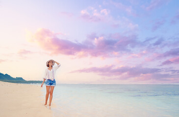 Fototapeta na wymiar Vacation on the seashore. Young woman walking on the beautiful tropical white sand beach.