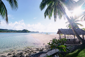 Vacation in paradise. Beautiful sunny landscape with sand tropical beach and green palm trees.