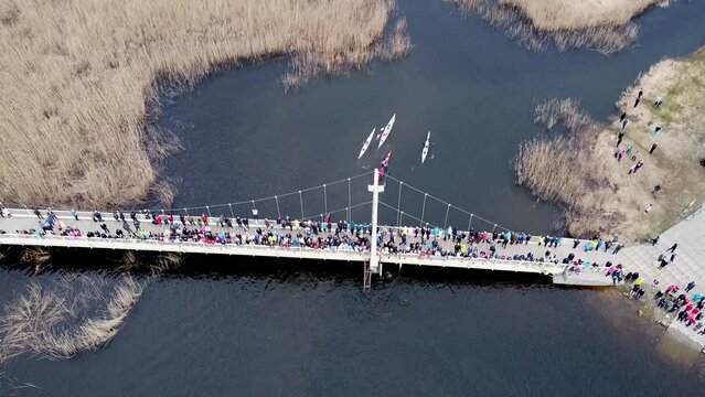 Top down view of following the canoes and kayaks on a river. Competition with boats. Water sports. Pro athletes competiting with eachother. People standing on abridge and looking