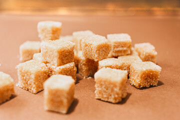 Brown sugar cubes close up on brown paper background