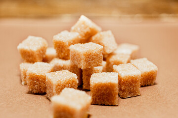 Brown sugar cubes close up on brown paper background