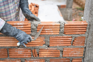 Construction worker installing bricks masonry bricklayer and adjusting bricks walls using trowel,...