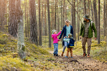 young family walking and exploring the forest with children. nature adventures - obrazy, fototapety, plakaty