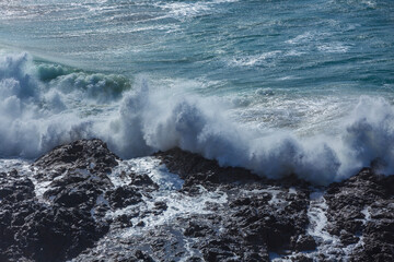 Big waves break against the rocks on a rough sea day