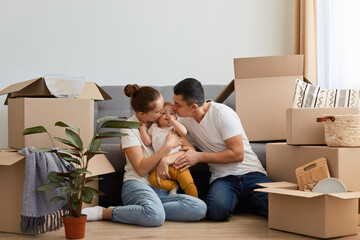 Image of young wife and husband posing in their new house on moving day, family with infant...