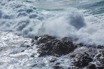Big waves break against the rocks on a rough sea day