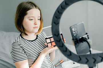 Caucasian teenager girl blogger recording a tutorial video for her beauty blog using smartphone