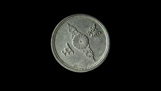 Rotating reverse of Japan coin 5 sen minted from 1940 till 1943 with inscription meaning FIVE SENS. Isolated in black background.