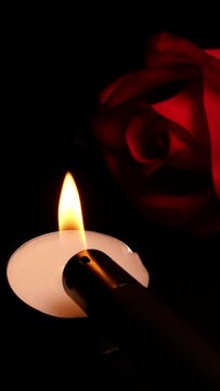 Roses and burning candles on black background as symbol mourning, memory or valentine day.