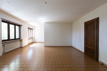 Large lounge with white walls and brown tiled floor. Interior vintage abandoned villa ready to be...