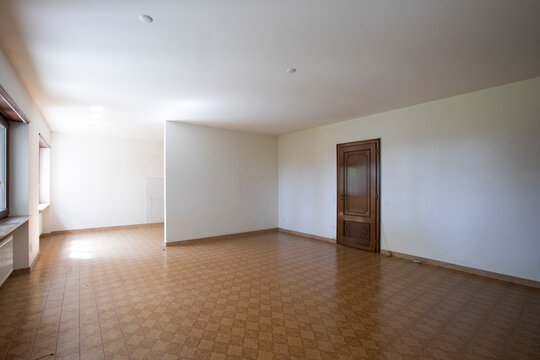 Large lounge with white walls and brown tiled floor. Interior vintage abandoned villa ready to be demolished
