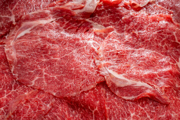 Obraz premium Close up shot Rare Sliced Wagyu beef with marbled texture on black plate, Meat red beef on wooden background, Asian shabu shabu Sukiyaki food style.