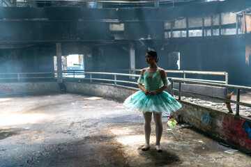 A young beautiful Asian ballerina is standing before ballet dancing in dark abandoned theater studio opera house with dim light. Photo of young female beauty of classical ballet art. Cinematic Style - Powered by Adobe