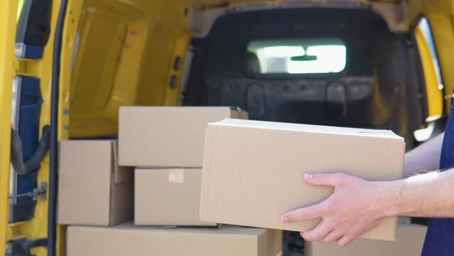 Cheerful courier throws the parcel standing near delivery van